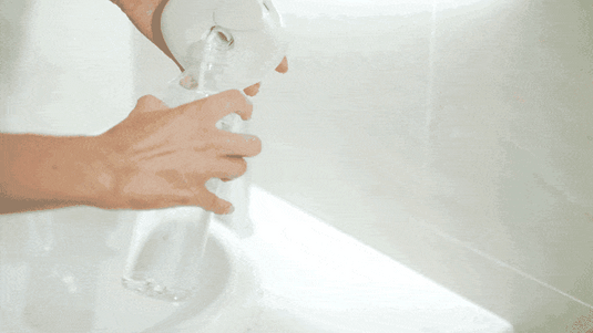 a woman is connecting a bottle water into flosmore fl02 water flosser