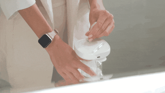 a woman is wearing a watch and put a nozzle into the flosmore fl02 water flosser